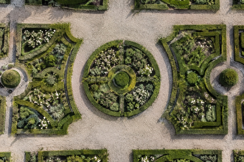 Geometrische tuin met lage hagen en grindpaden, recht van boven gezien
